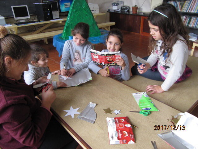 Um grupo de alunas está a contornar moldes de estrelas de Natal nas caixas da guloso.