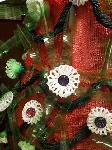Flores realizadas com garrafas de plástico de sumo, com cápsulas de café e com plástico protetor de garrafas de vidro.